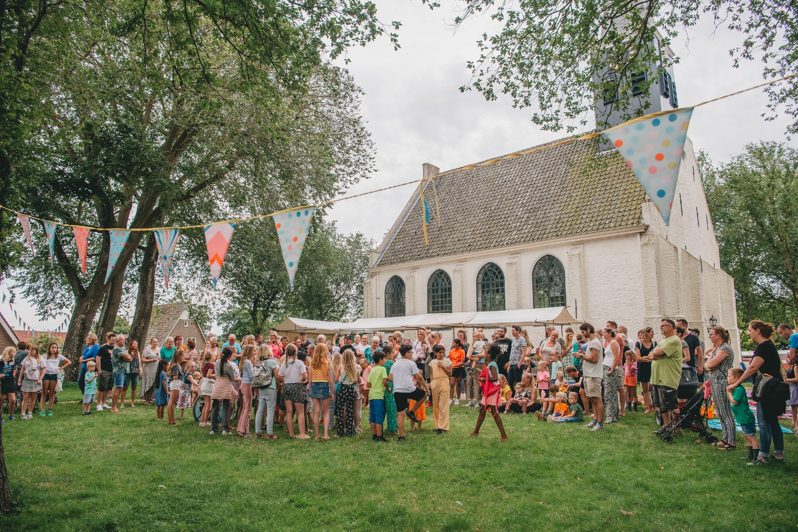 Zomergroet met feesttentjes en vlaggetjes bij het witte kerkje in Groet